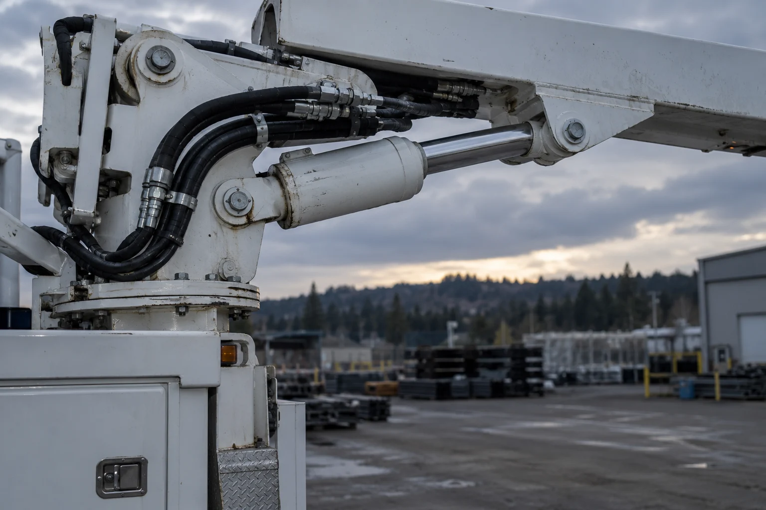 Close view of bucket truck hydraulic hoses, cylinder and boom pivot